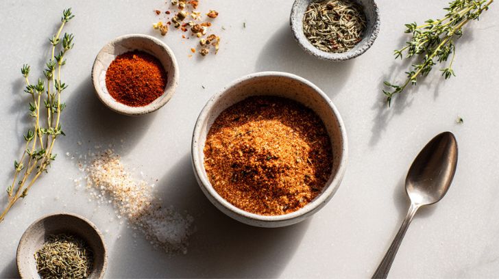 top down view van een schaal gevuld met cajun kruiden met wat andere kruiden en specerijen ernaast